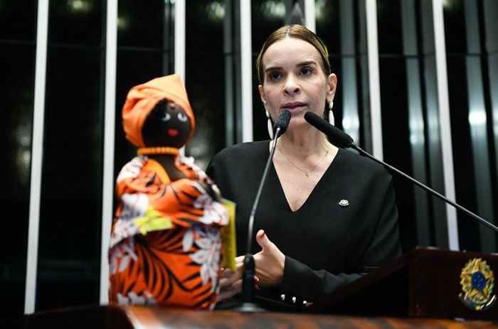 Daniella Ribeiro exibe boneca-simbolo do banco de Leite Materno de Angola na cor predominante do Agosto Dourado - Foto: Roque de Sá/Agência Senado